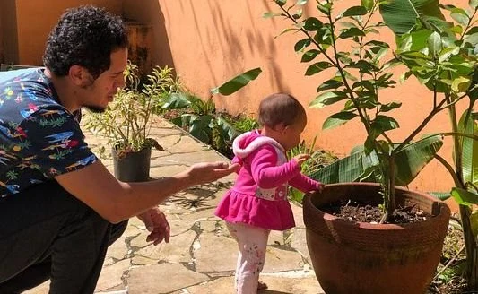 Elcio e a filha cuidando de uma planta no quintal
